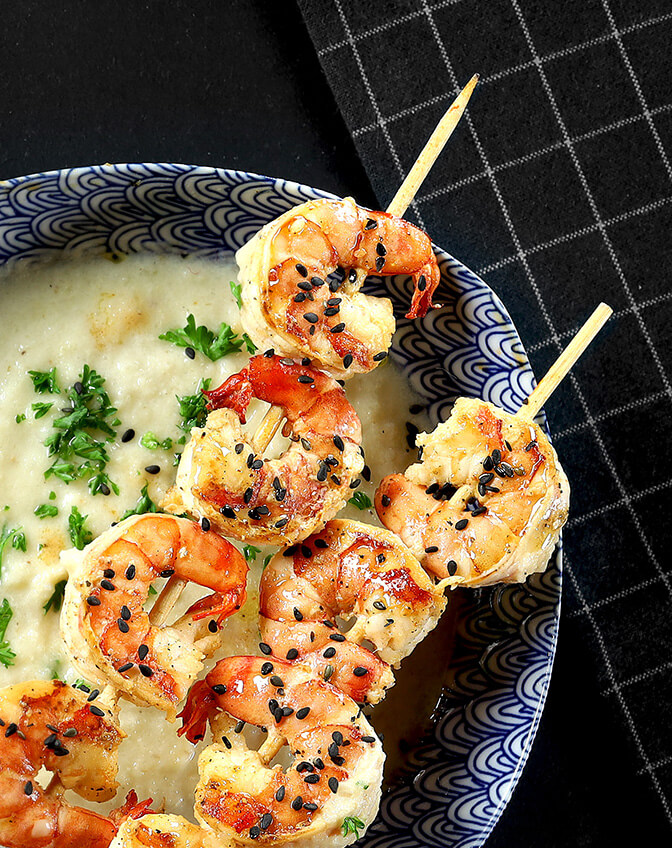 Blumenkohlsuppe mit Garnelenspieß angerichtet